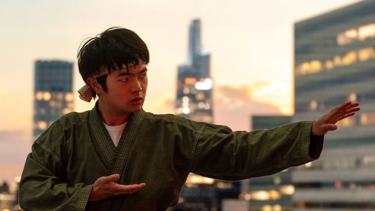 Karakter Li Fong (diperankan oleh Ben Wang) sedang berlatih karate di atap gedung dengan latar belakang matahari terbenam dan kota modern. Ia mengenakan pakaian bela diri tradisional dan ikat kepala, menggambarkan tekad dan semangat dalam perjuangan menghadapi tantangan. Gambar ini menunjukkan momen pelatihan intensif karakter utama dalam Karate Kid: Legends (2025).