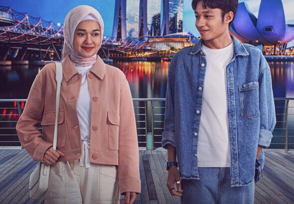 Poster film Ahlan Singapore (2026) menampilkan dua karakter utama, seorang wanita berhijab dan seorang pria, berdiri di depan latar belakang Marina Bay Sands Singapura dengan cahaya kota yang memukau. Mereka tersenyum, menunjukkan chemistry yang hangat di bawah langit malam yang penuh bintang.