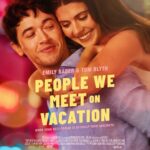 Poster film People We Meet on Vacation menampilkan Emily Bader dan Tom Blyth yang berpelukan dengan latar belakang bercahaya kota, menunjukkan kedekatan emosional mereka.