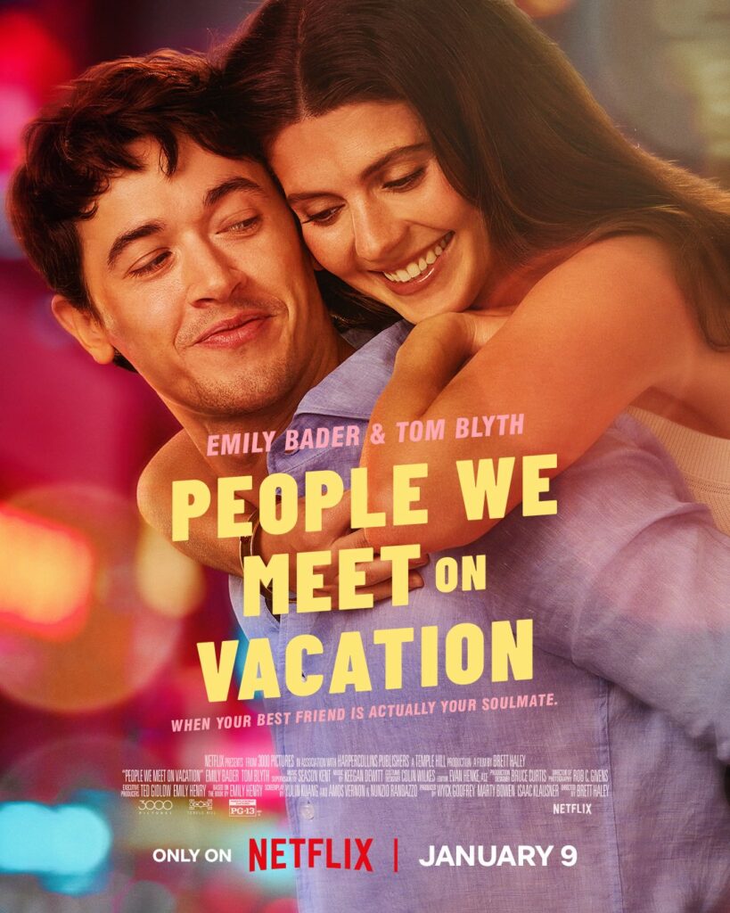 Poster film People We Meet on Vacation menampilkan Emily Bader dan Tom Blyth yang berpelukan dengan latar belakang bercahaya kota, menunjukkan kedekatan emosional mereka.