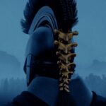 Poster film The Odyssey (2026) dengan tampilan belakang seorang prajurit menggunakan helm khas dengan desain yang mencolok, menunjukkan kesan epik dan misterius.