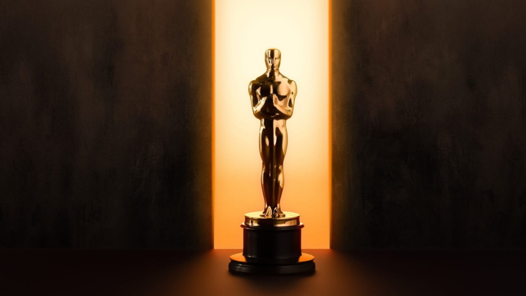 Patung Oscar emas berdiri di atas podium dengan cahaya dramatis dari belakang