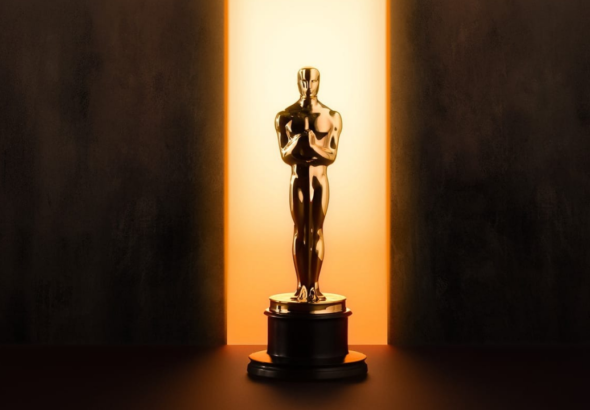 Patung Oscar emas berdiri di atas podium dengan cahaya dramatis dari belakang