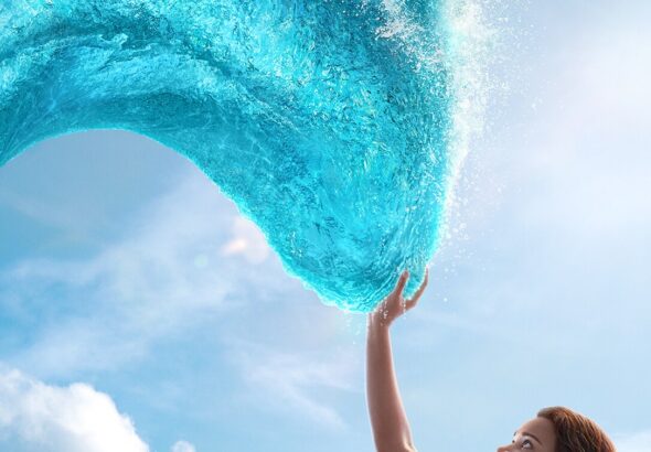 Seorang gadis mengangkat tangan menyentuh gelombang laut berbentuk lengkungan di langit dengan latar awan cerah, menggambarkan adegan dari Moana (Live-Action).